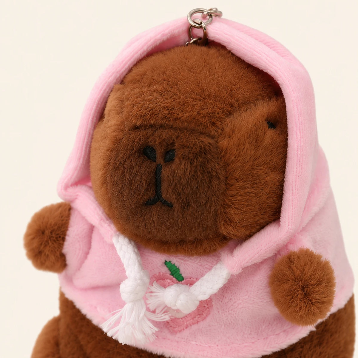 Peluche porte-cles capybara a capuche rose, gros plan sur le visage