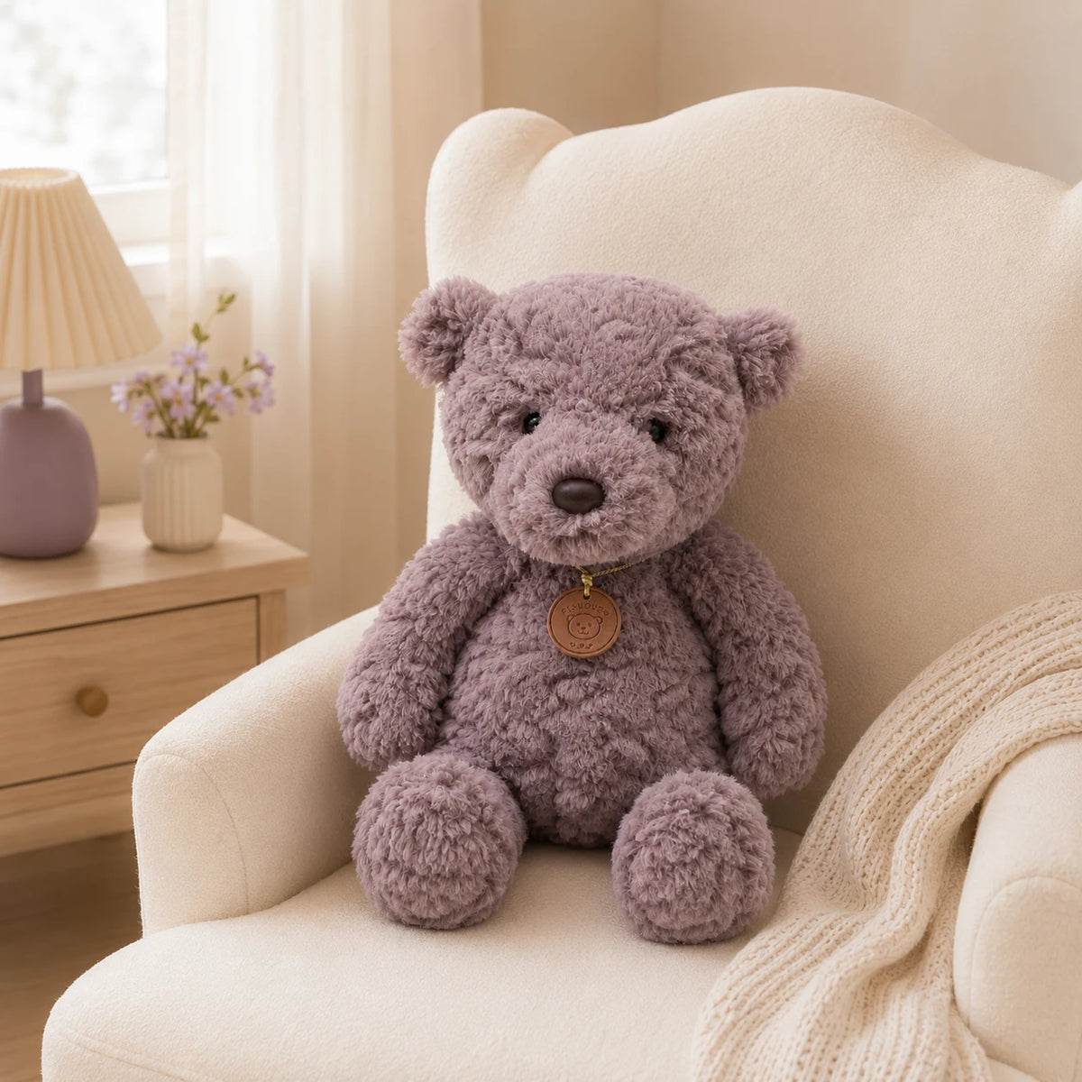 Peluche ours gris installée dans un fauteuil crème d'une chambre lumineuse