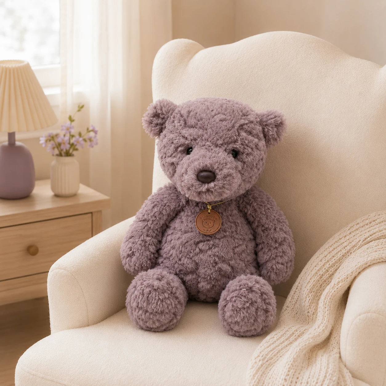 Peluche ours gris installée dans un fauteuil crème d'une chambre lumineuse
