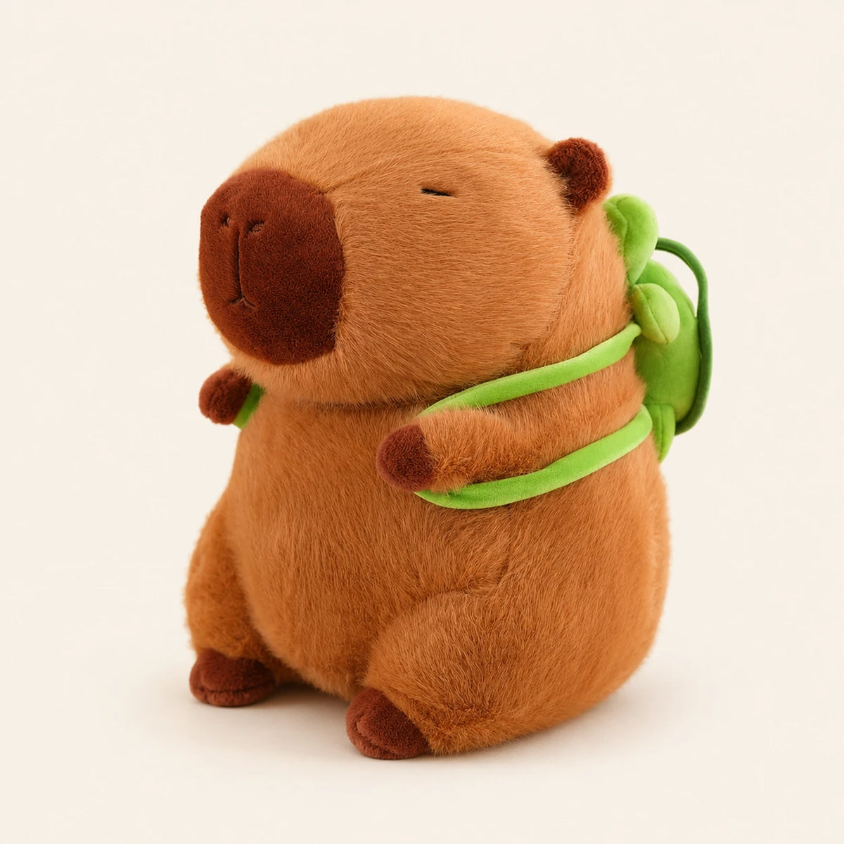 Peluche capybara avec sac à dos tortue, vue de face, environ 30 cm, fond ivoire