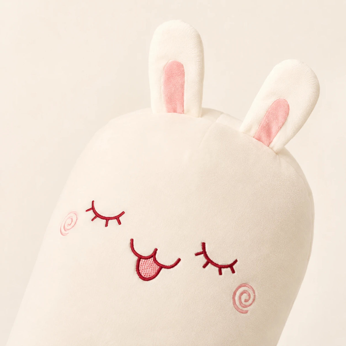 Gros plan sur le visage brodé et les oreilles du coussin lapin