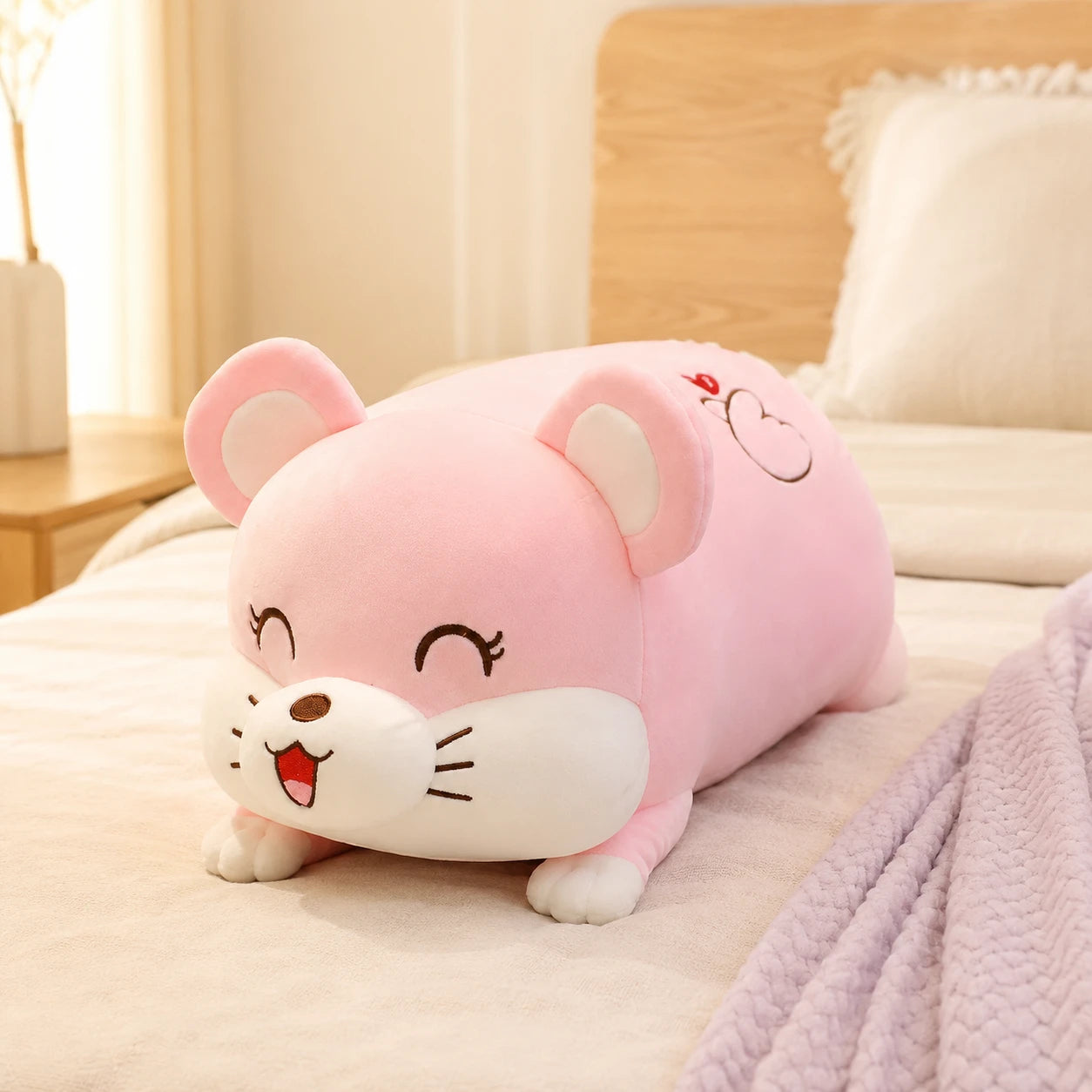 Coussin peluche rose posé sur un lit douillet