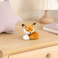 Mini renard peluche pose sur une table de chevet en bois clair