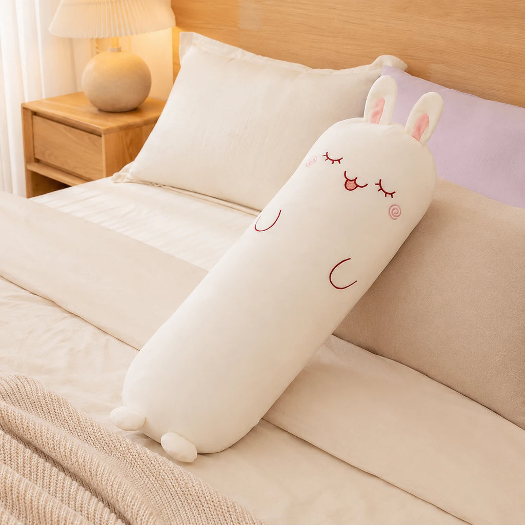 Long coussin peluche lapin posé sur un lit douillet