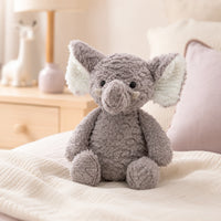 Peluche éléphant longues pattes 37 cm posée sur un lit