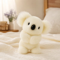 Peluche koala blanche posée sur un lit douillet