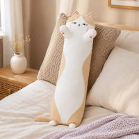 Coussin long peluche chat pose sur un lit douillet