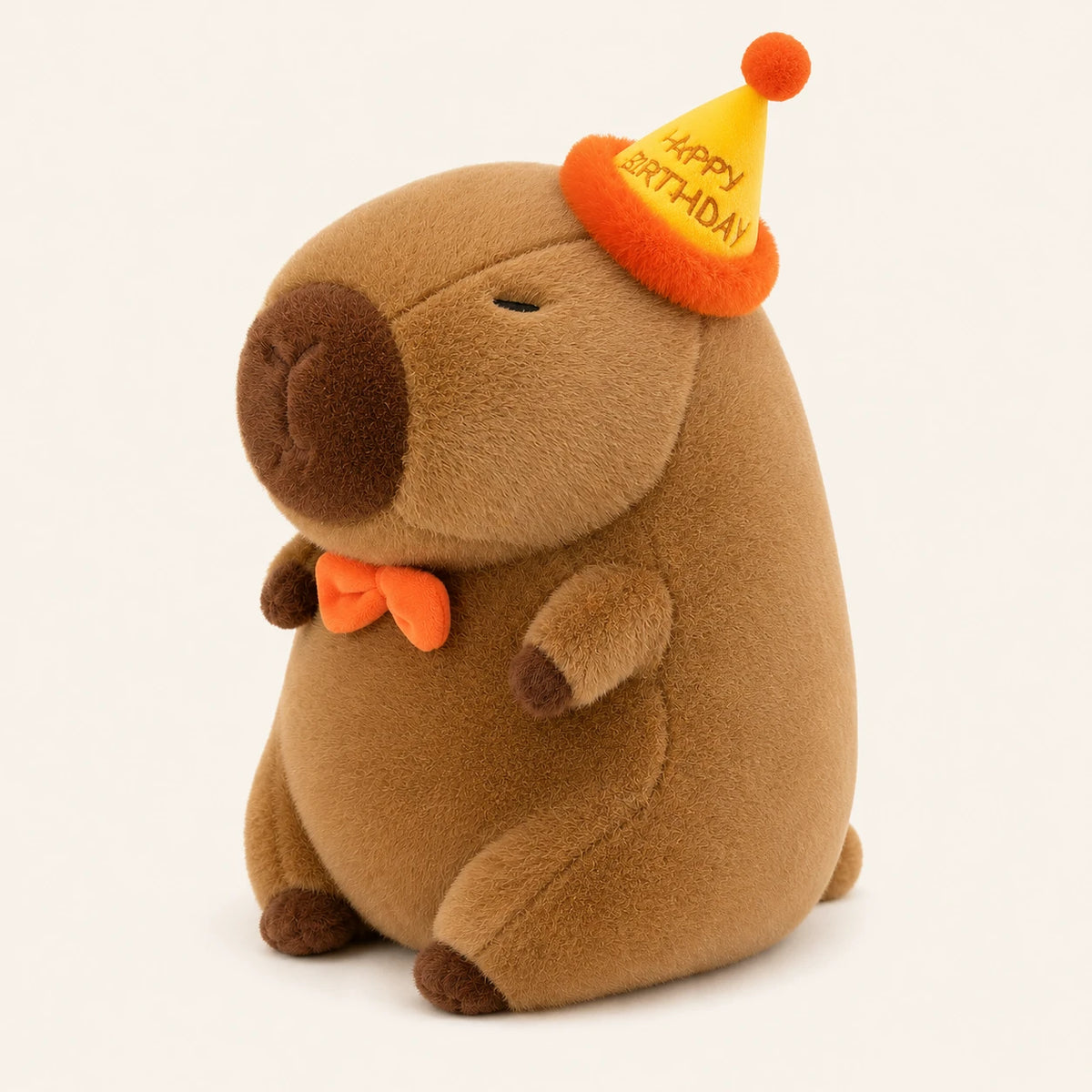Peluche capybara avec chapeau d'anniversaire, vue de trois-quarts, fond ivoire