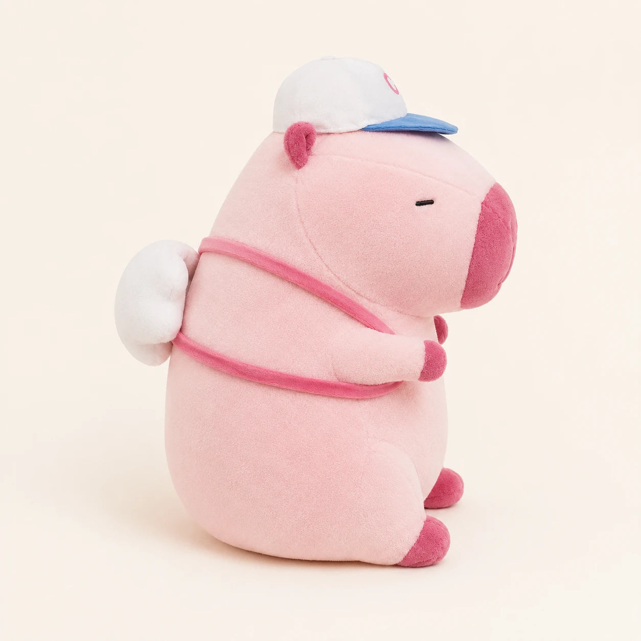 Peluche capybara rose avec casquette, vue de trois-quarts arriere