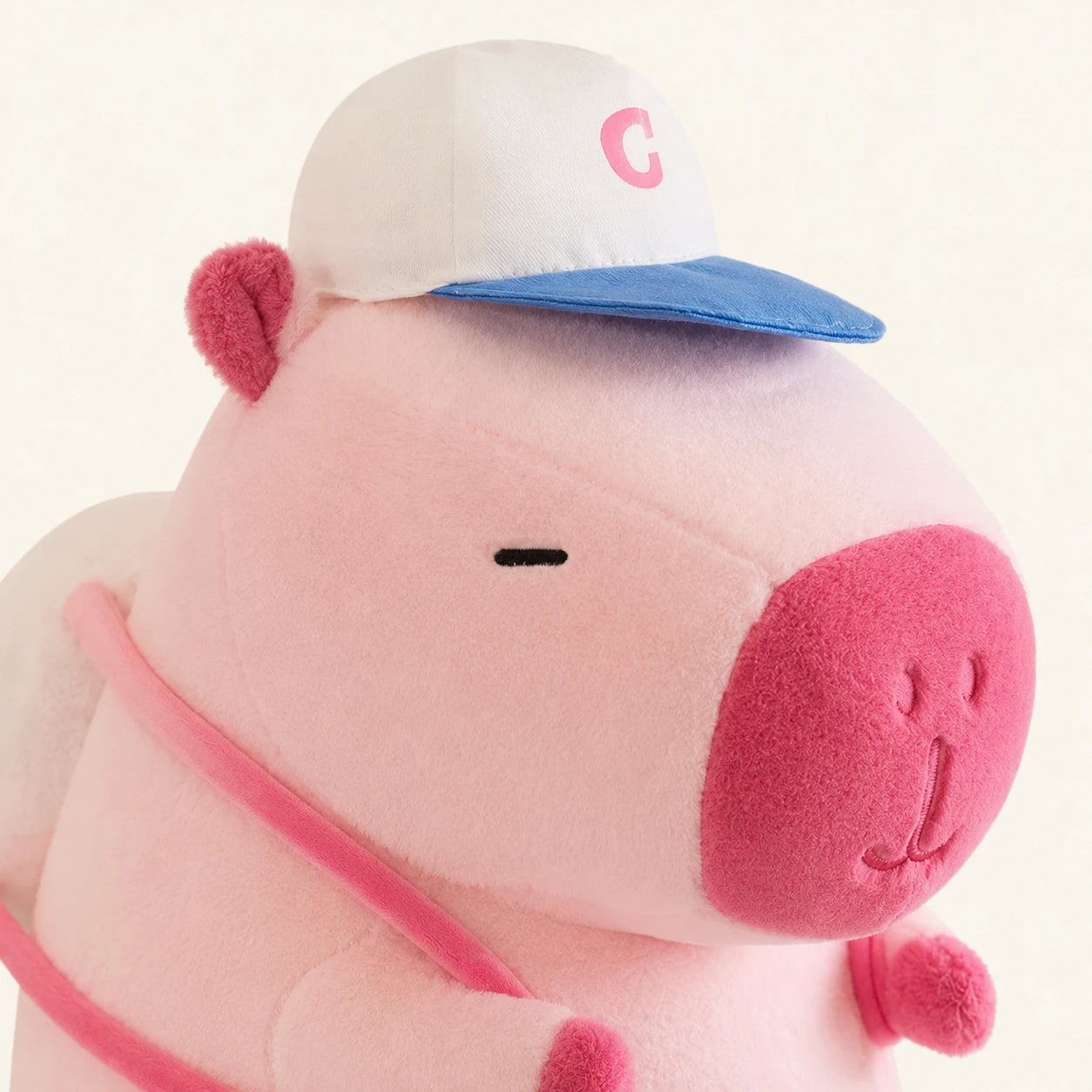 Peluche capybara rose, gros plan sur le visage et la casquette