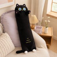 Long coussin peluche chat noir posé sur un canapé clair