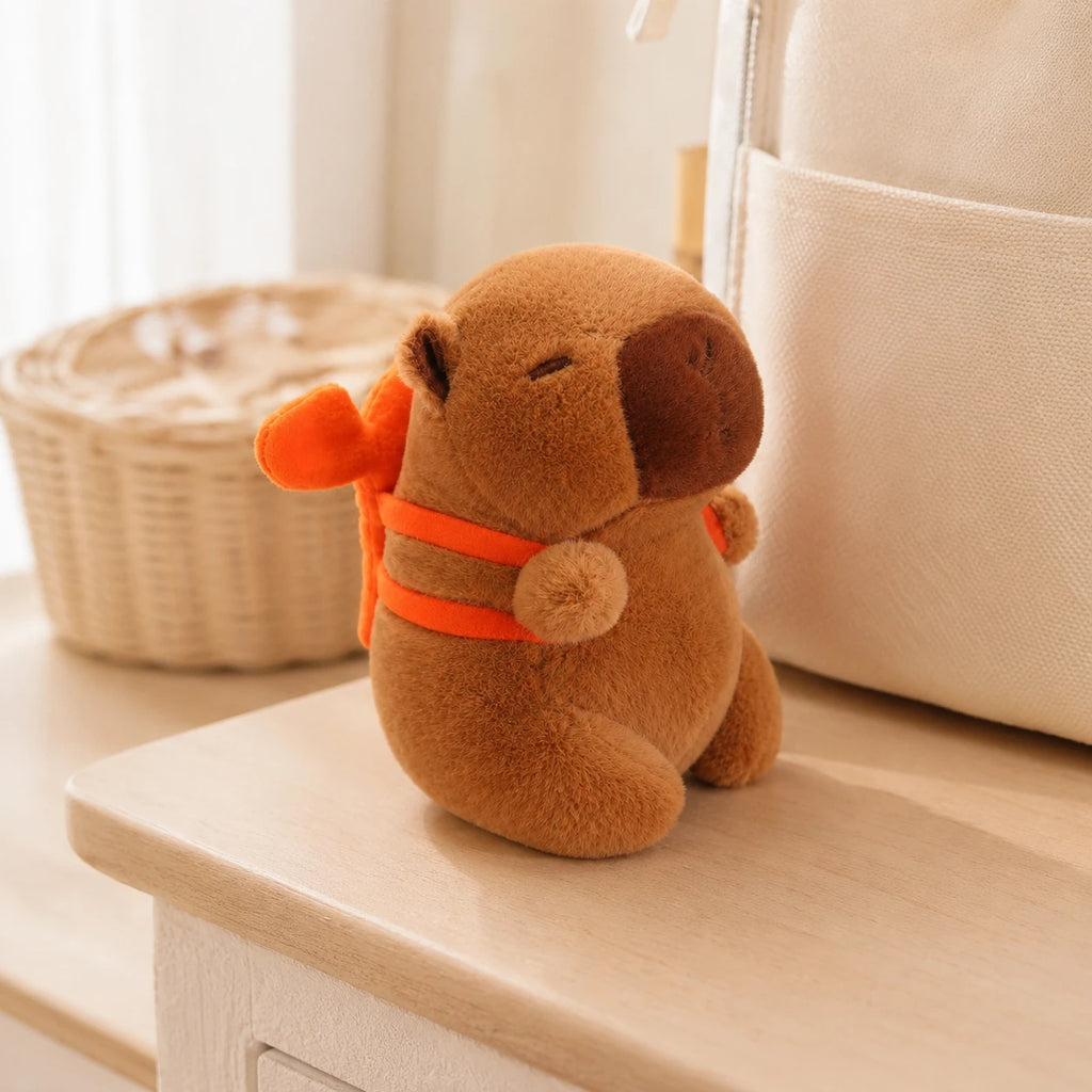 Peluche capybara au sac orange posée sur une étagère