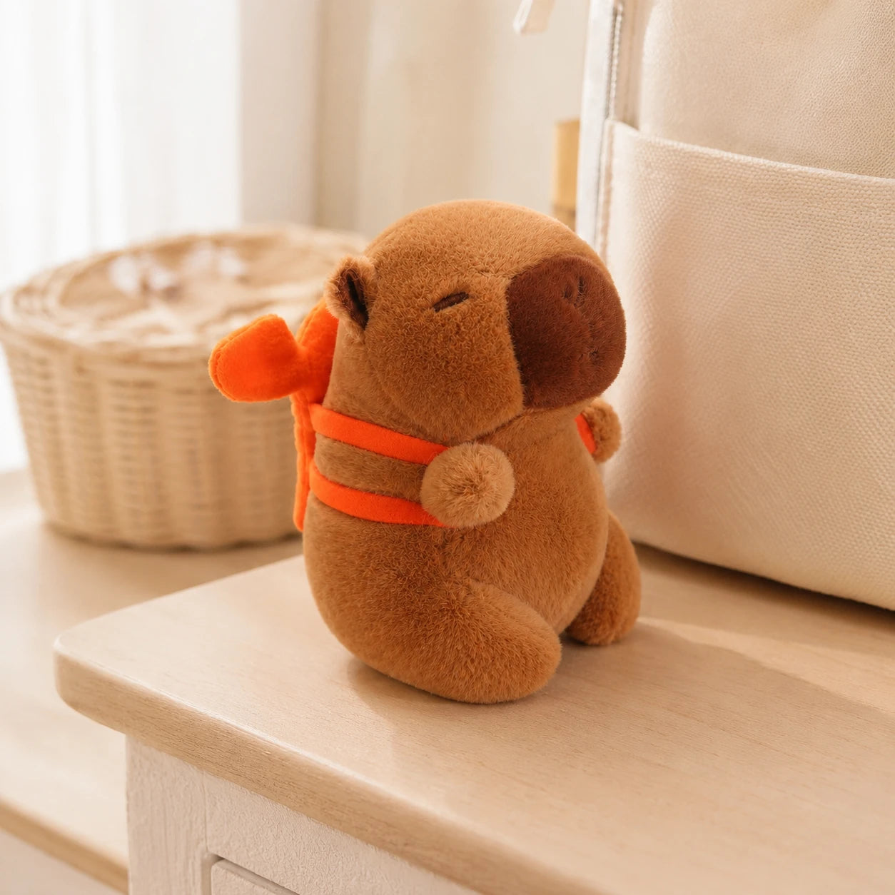 Peluche capybara au sac orange posée sur une étagère