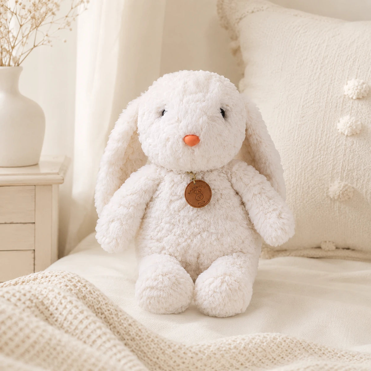 Peluche lapin blanc longues pattes 35 cm posée sur un lit