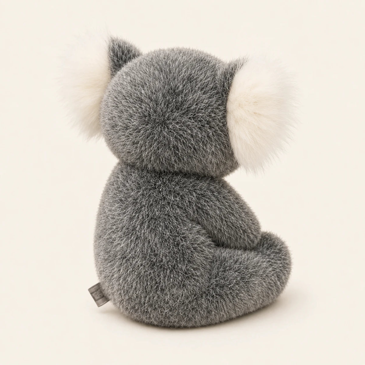 Peluche koala grise vue de dos sur fond ivoire