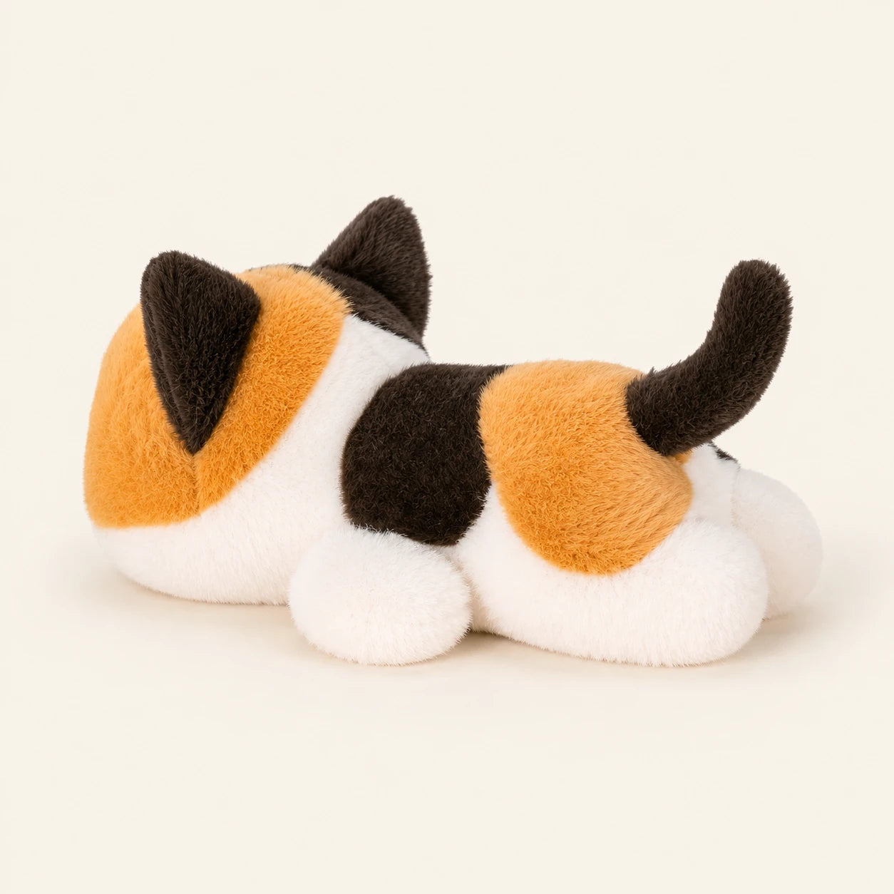 Peluche chaton tricolore vue de côté, fond ivoire