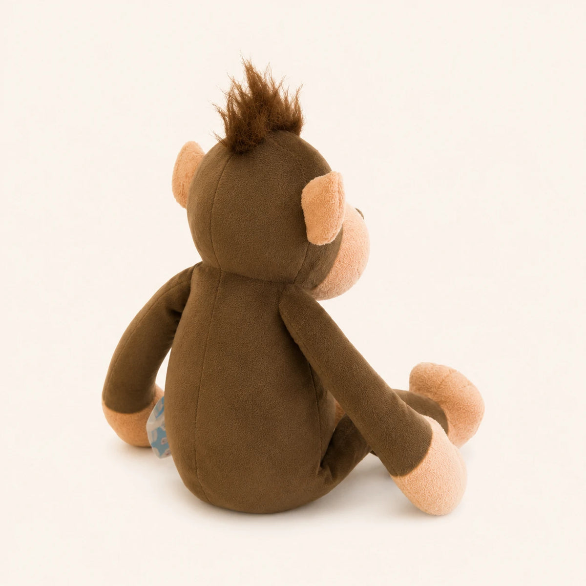 Peluche singe brun vue de dos trois-quarts, fond ivoire