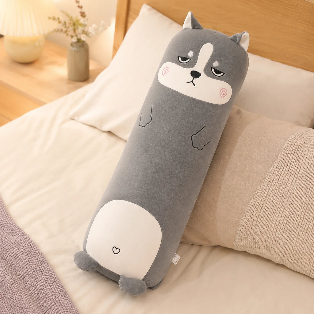 Coussin long peluche husky pose sur un lit douillet