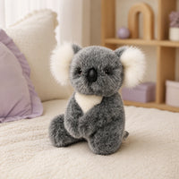 Peluche koala grise posée sur un lit douillet, ambiance chaleureuse