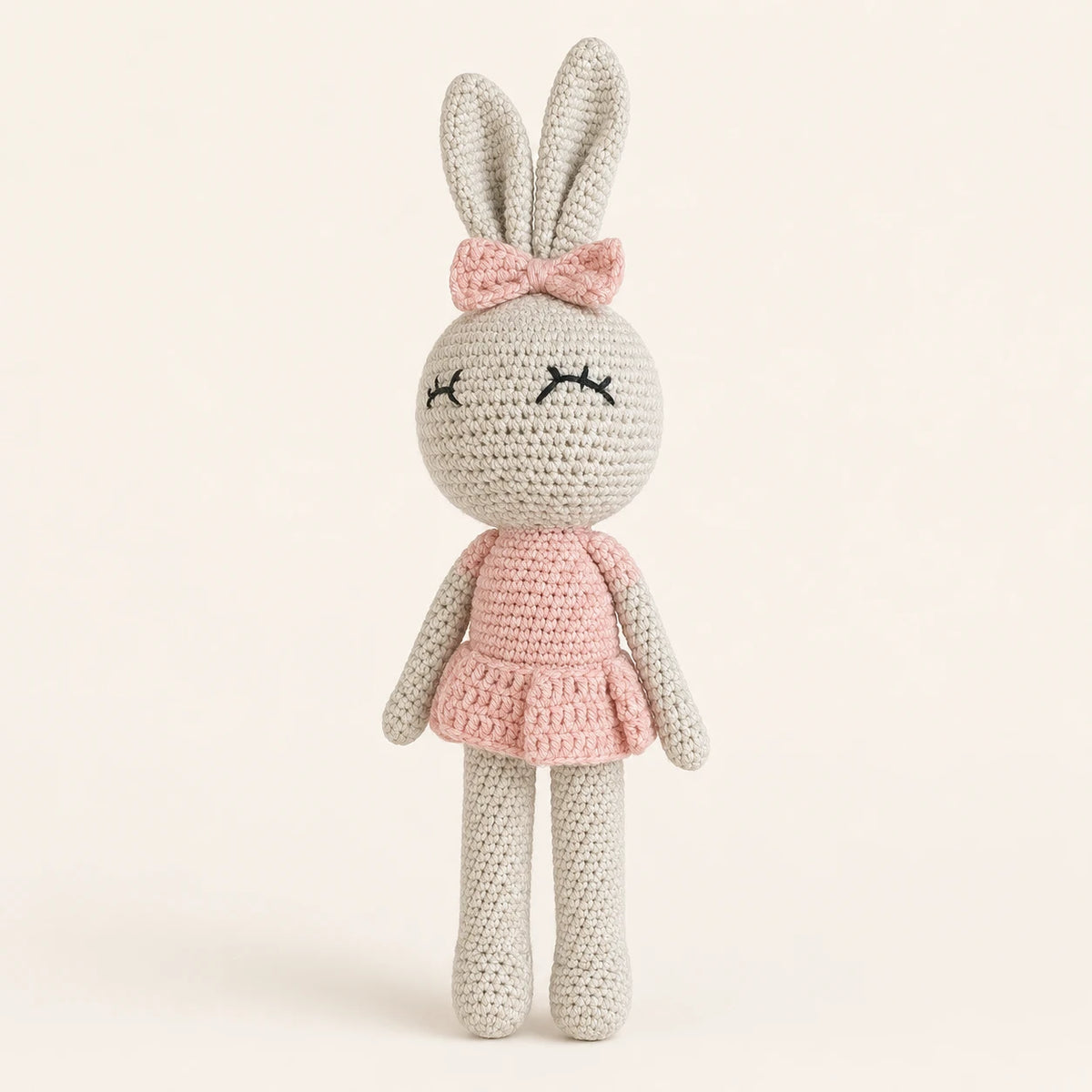 Poupée lapin au crochet en robe rose, vue de face sur fond ivoire