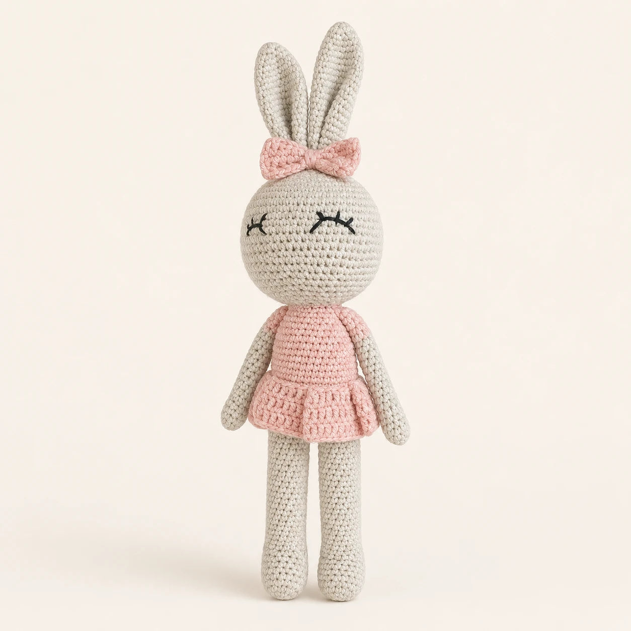 Poupée lapin au crochet en robe rose, vue de face sur fond ivoire