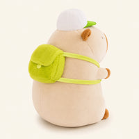 Peluche capybara creme, vue de trois-quarts arriere montrant le sac a dos vert