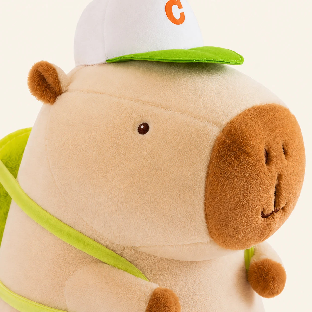 Peluche capybara creme, gros plan sur le visage et la casquette