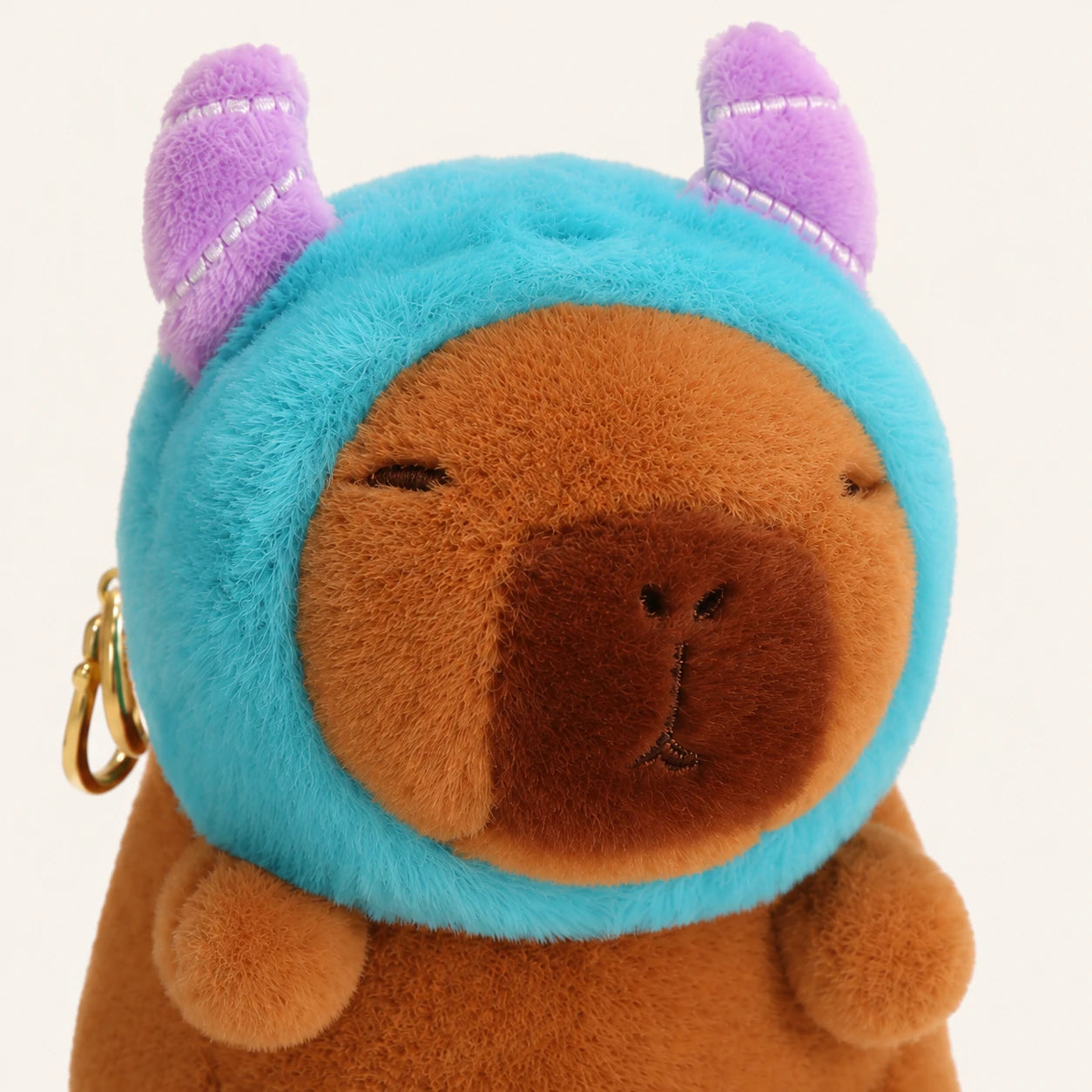 Gros plan sur le visage de la peluche capybara au bonnet bleu