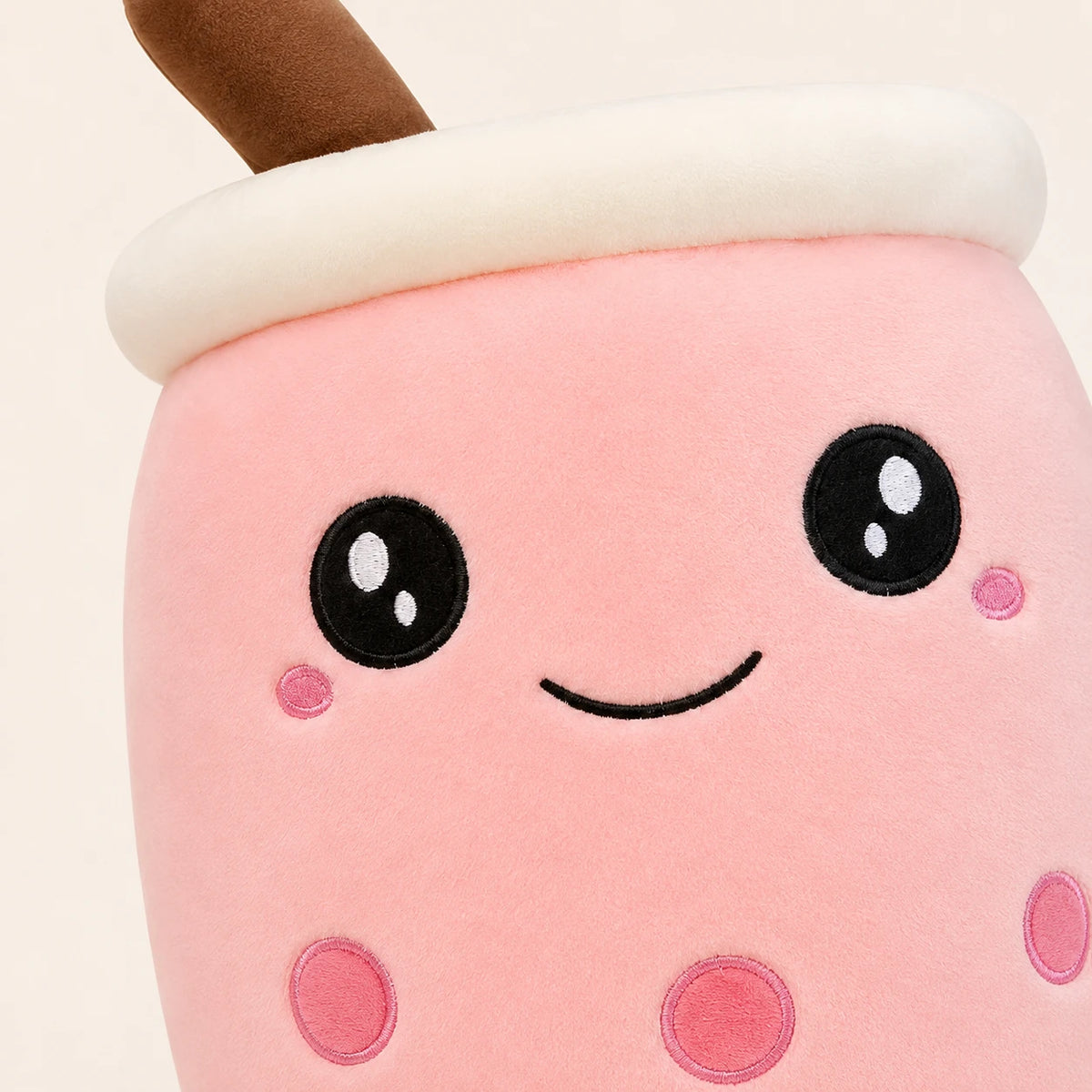 Gros plan sur le visage brodé de la peluche bubble tea rose