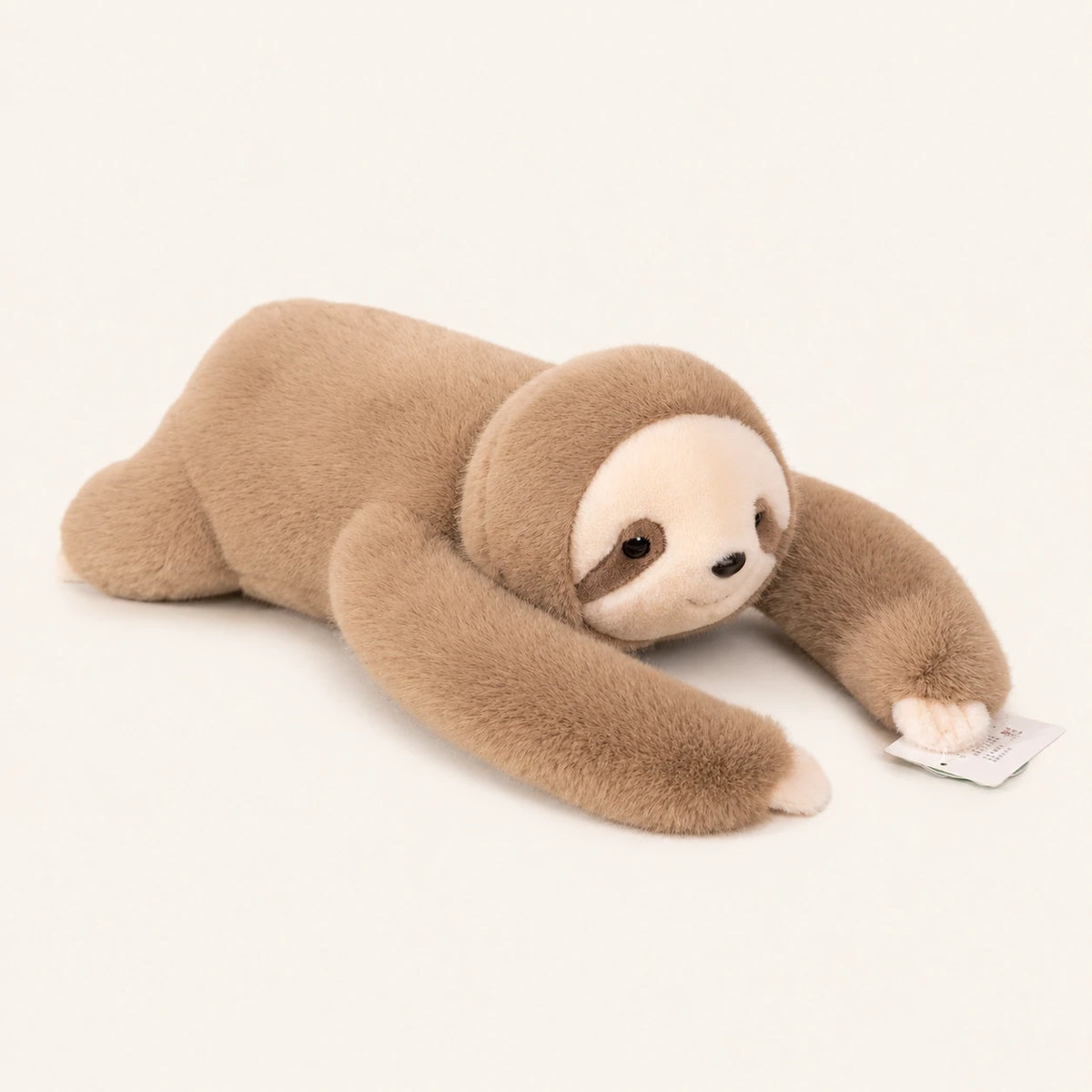 Peluche paresseux beige allongée, vue de face, fond ivoire