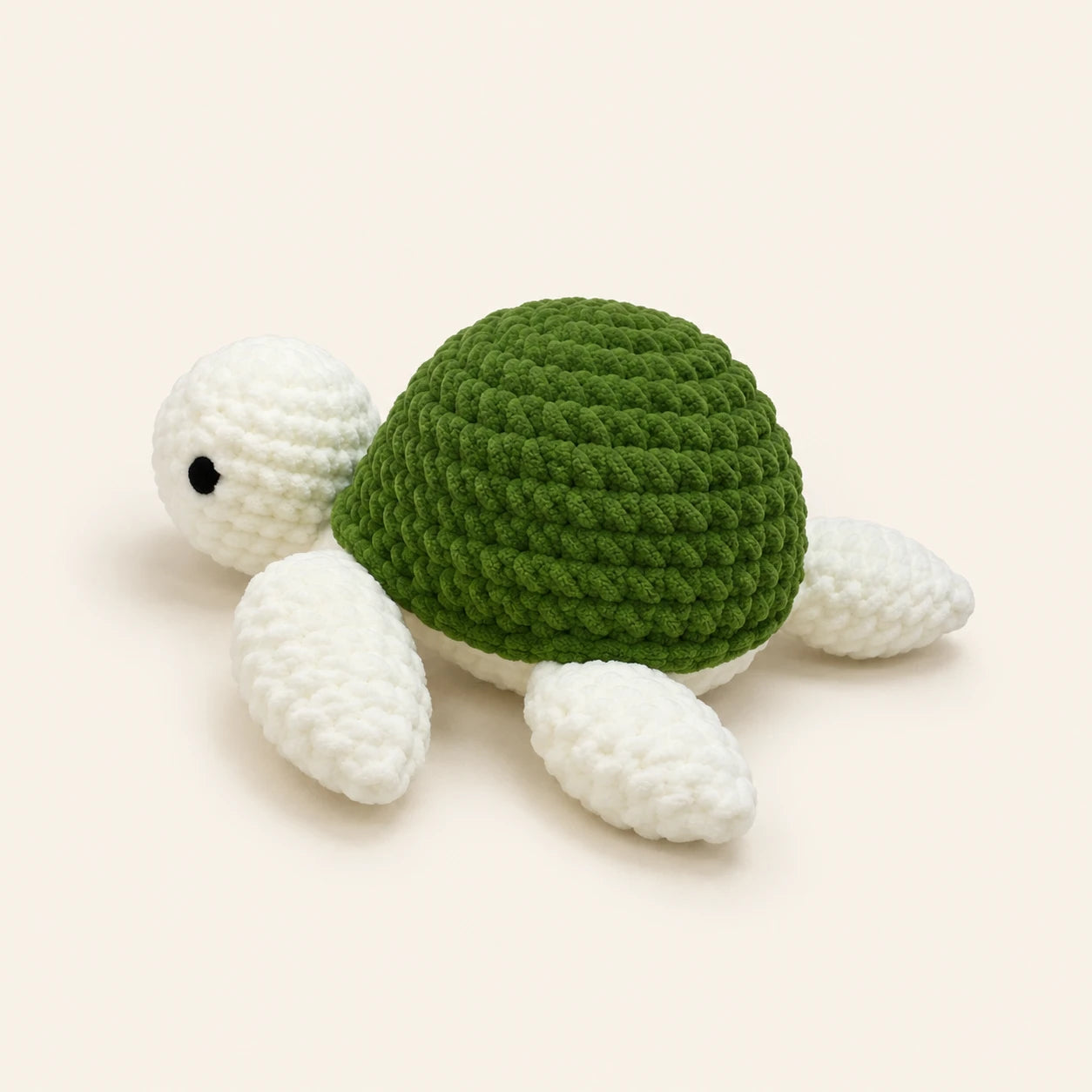 Peluche tortue au crochet verte, vue de trois-quarts, fond ivoire