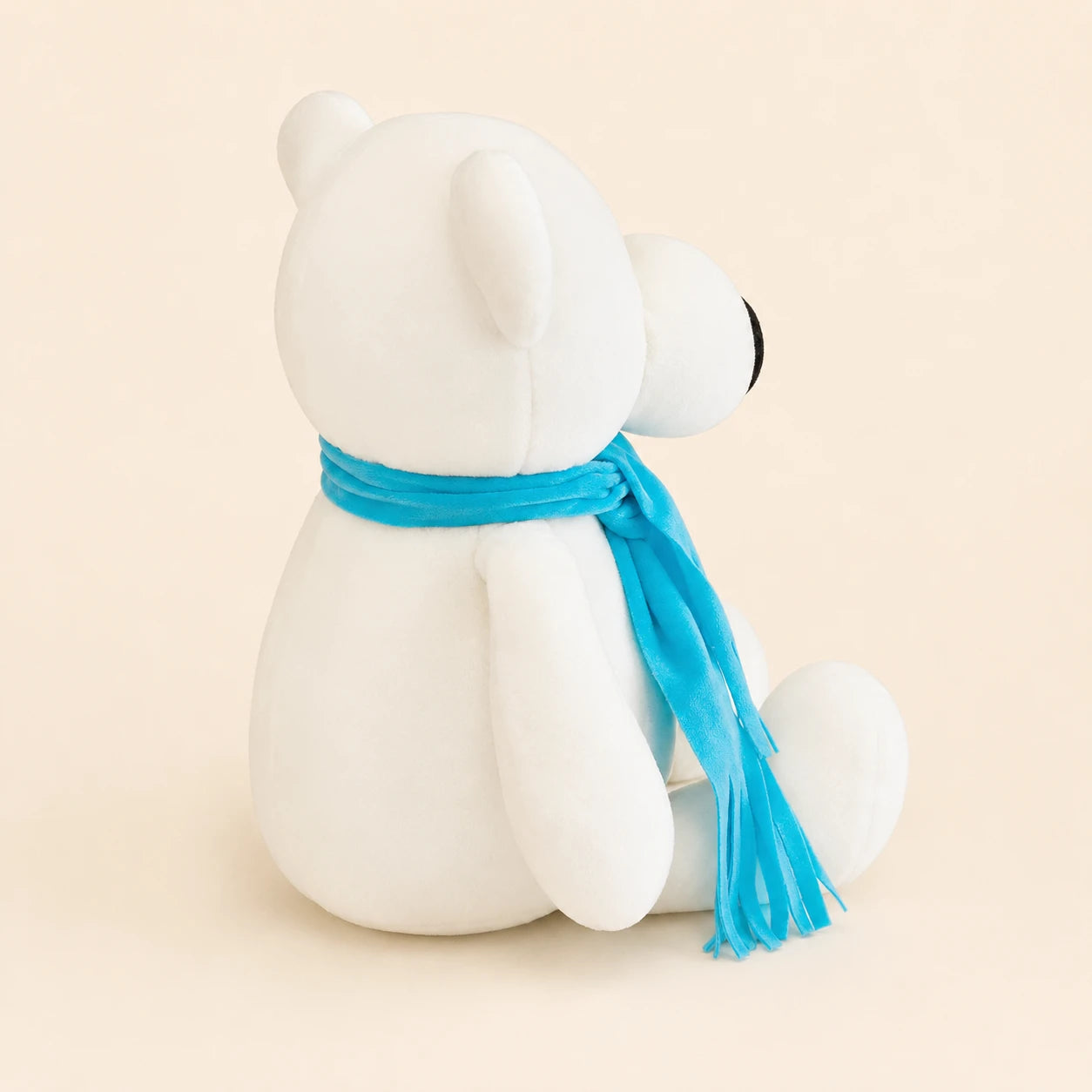Peluche ours polaire vue de dos, écharpe bleue, fond ivoire