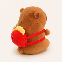 Peluche capybara vue de côté montrant le sac à dos, fond ivoire