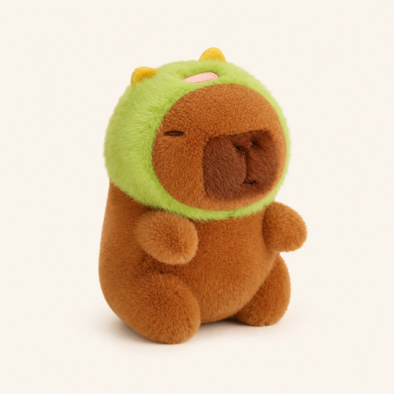 Peluche capybara avec capuche verte, vue de face, fond ivoire