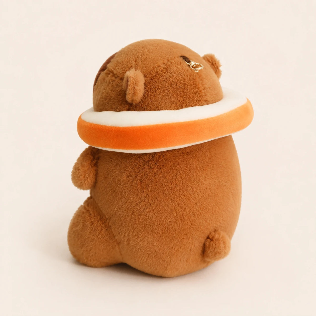 Peluche capybara avec bouée orange, vue de face, fond ivoire