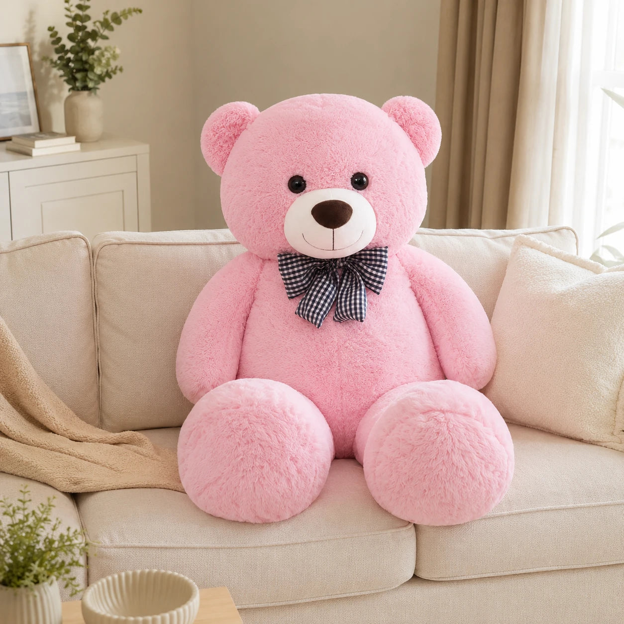 Grand ours en peluche rose 105 cm pose sur un canape creme