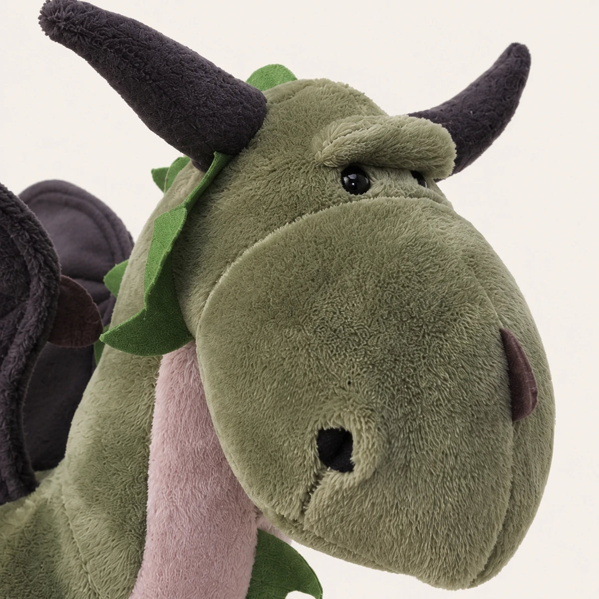 Gros plan sur le visage et la texture de la peluche dragon vert